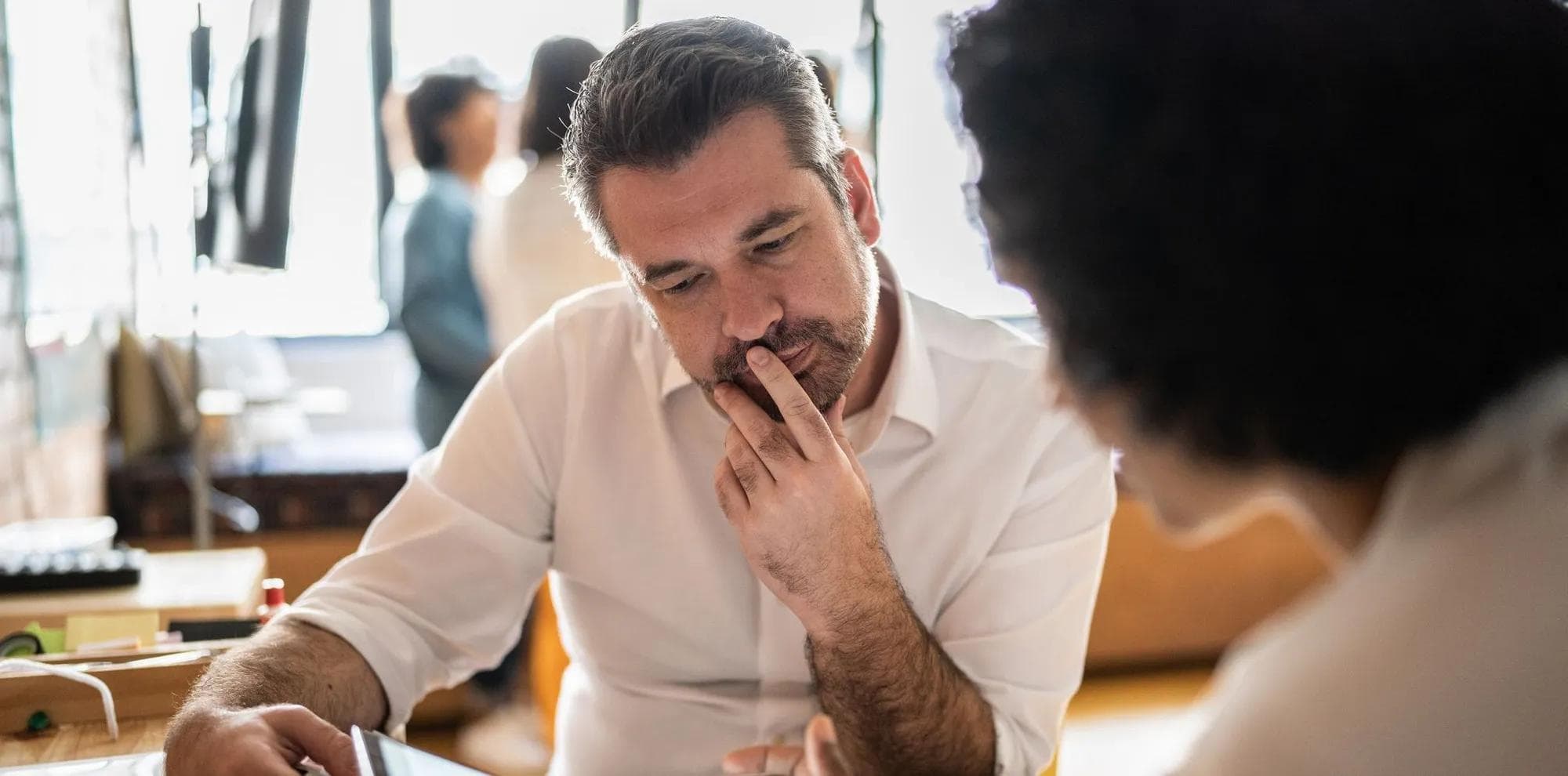 Mature man looking at a digital tablet that a colleague is showing at work
