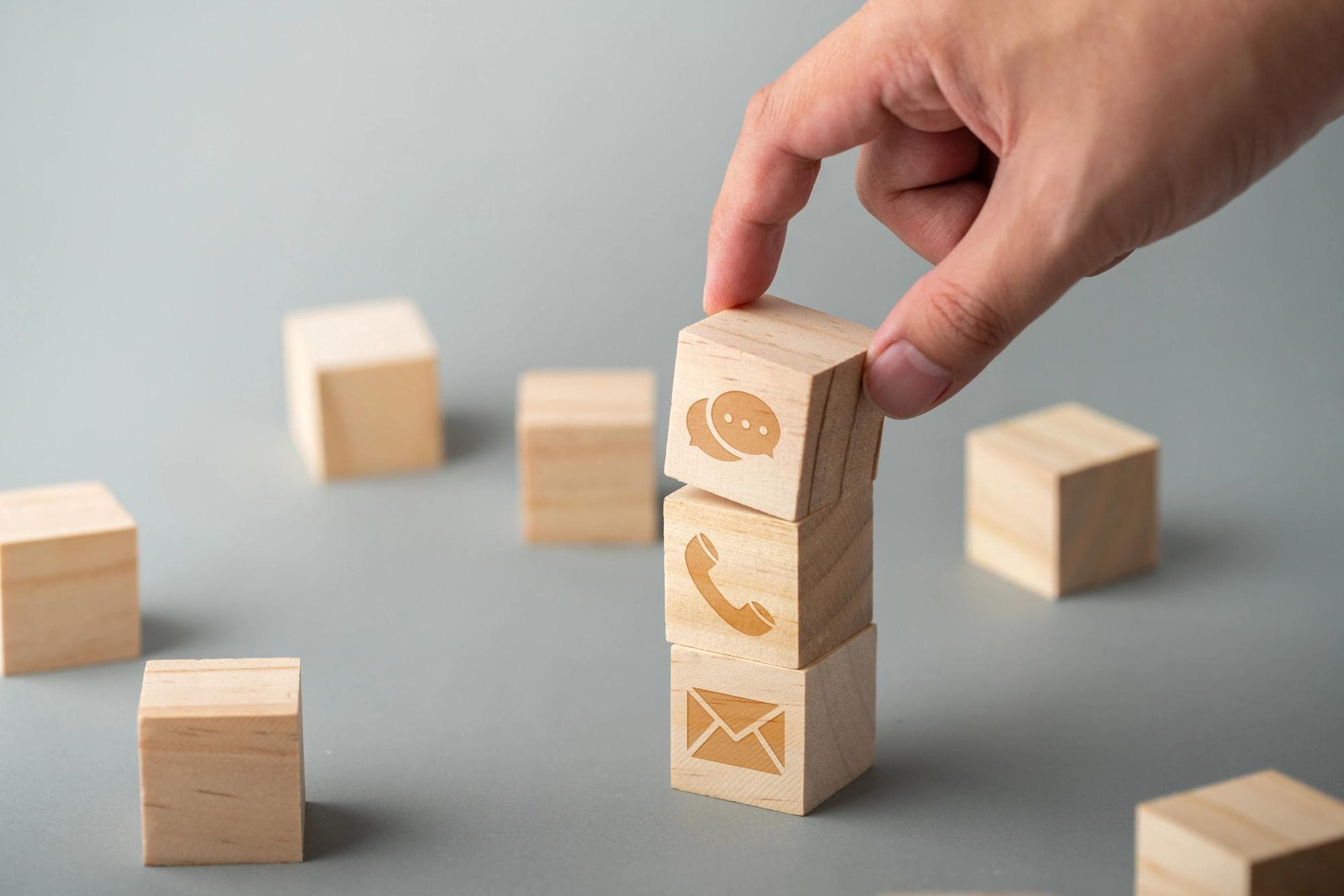 Blocs de bois ornés d’icônes représentant une enveloppe et un téléphone, illustrant les procédures de contre-appel comme pratique de gestion des risques. 