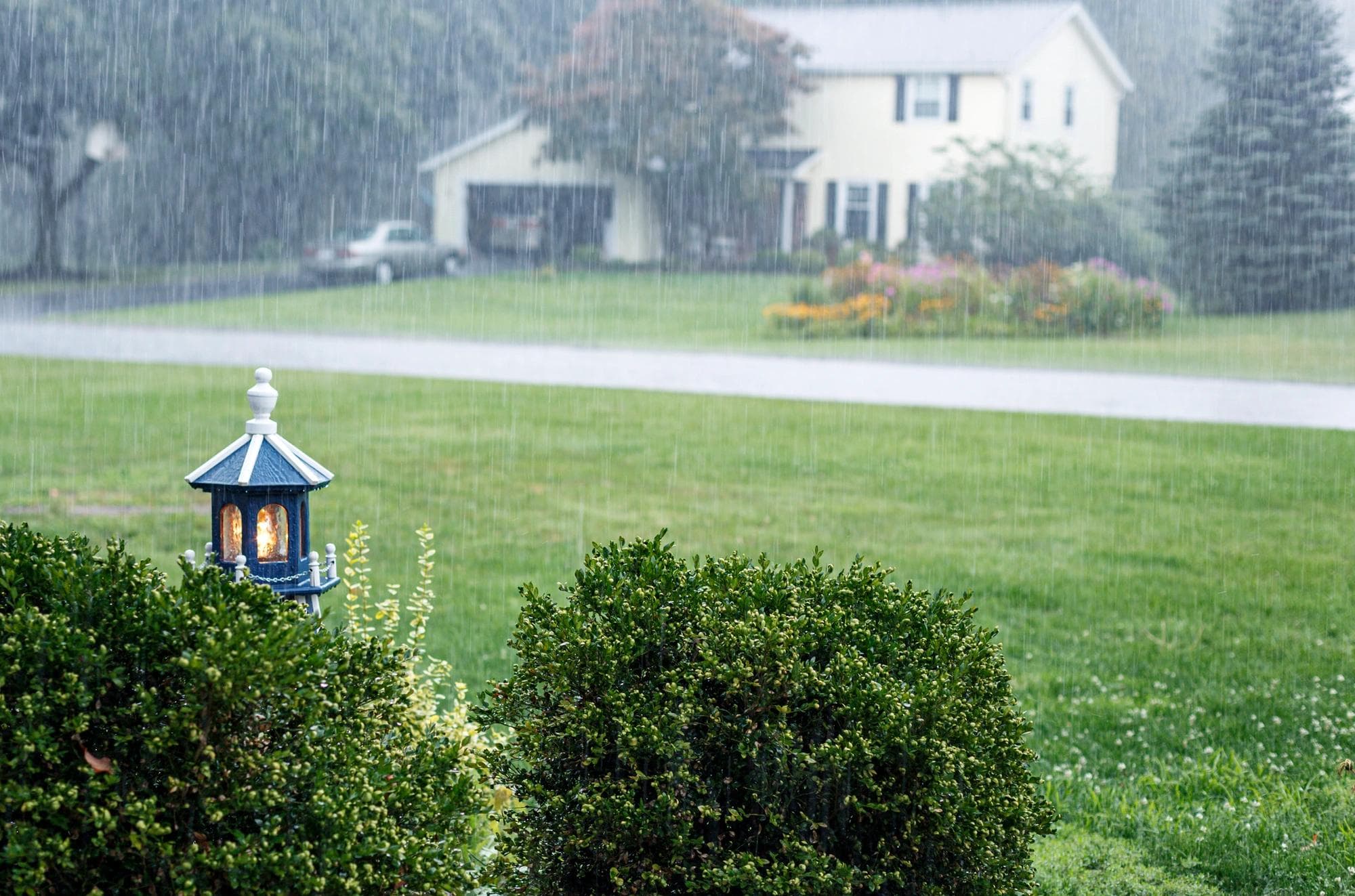A front yard wooden replica model lighthouse is illuminated during a drenching downpour in a neighborhood in New York State. 